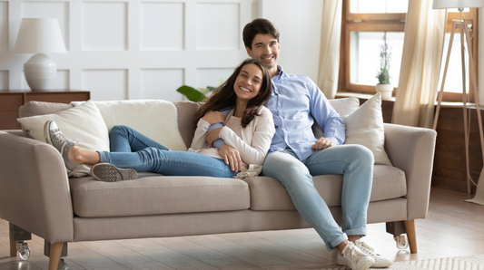 A smiling couple sitting together on a sofa in a cozy living room.