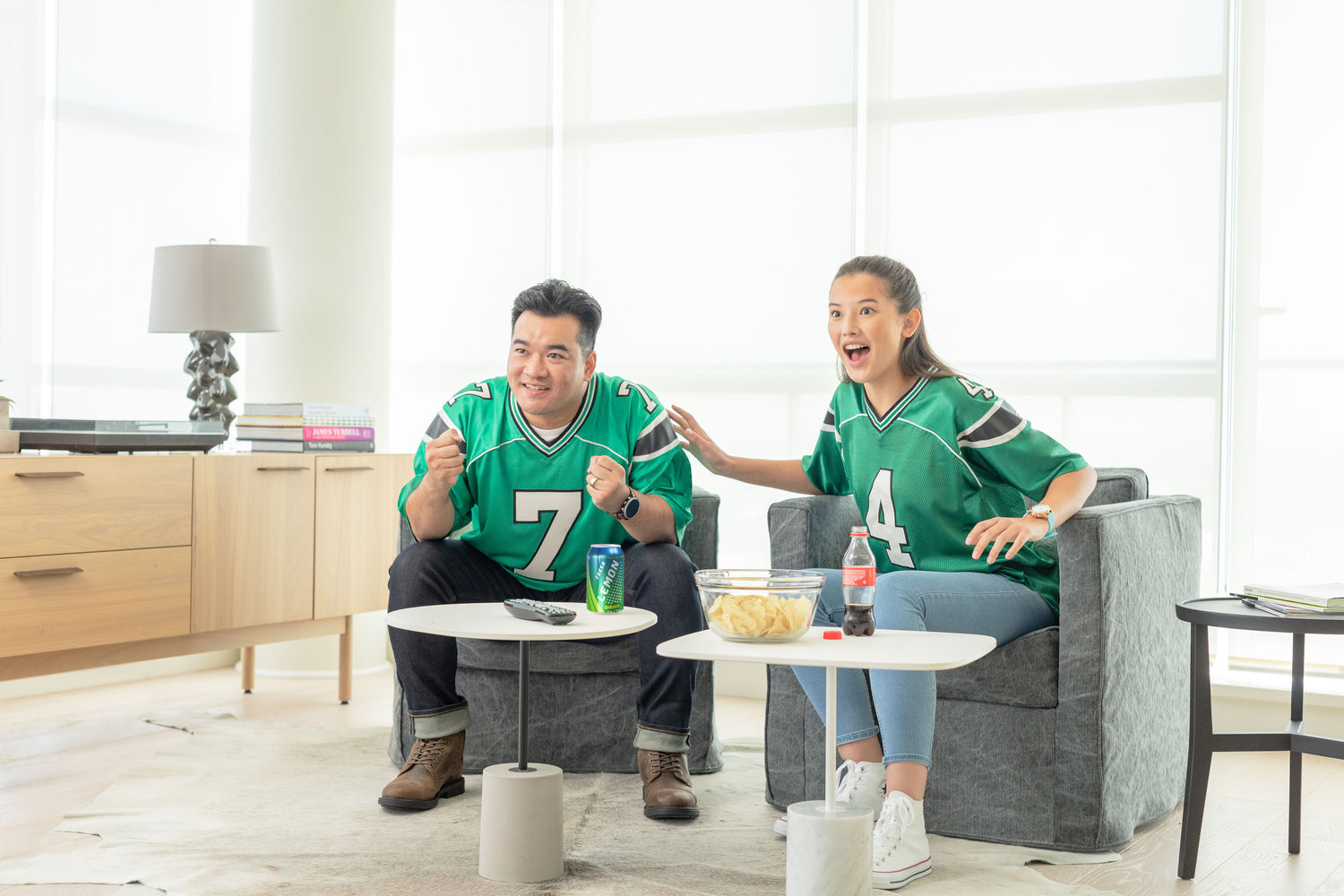 A Dad And Daughter Wearing Jerseys, Watching Sports Together